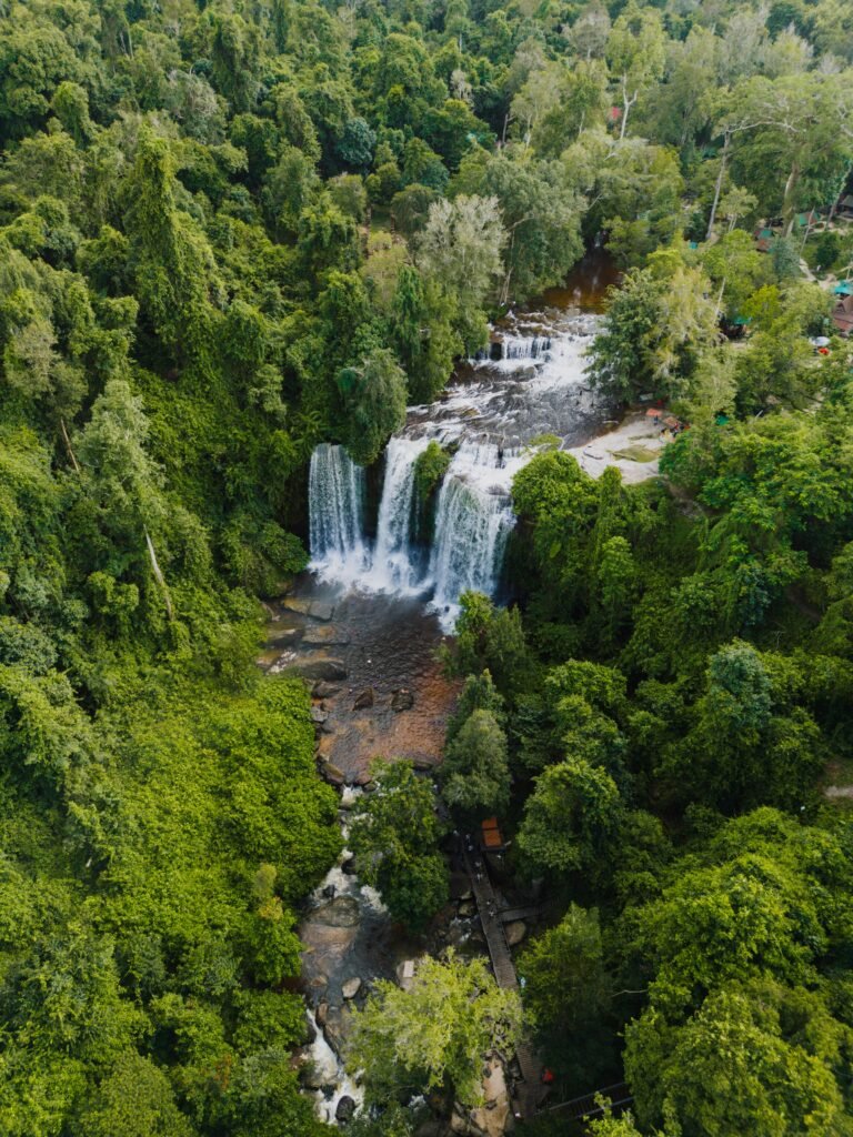 Captivating aerial view of lush green forest surrounding Phnom Kulen Waterfalls in Siem Reap, Cambodia.
