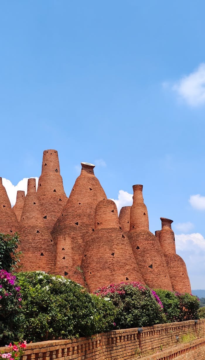 about-01 Traditional red brick chimneys standing tall against a vibrant blue sky with floral foreground.