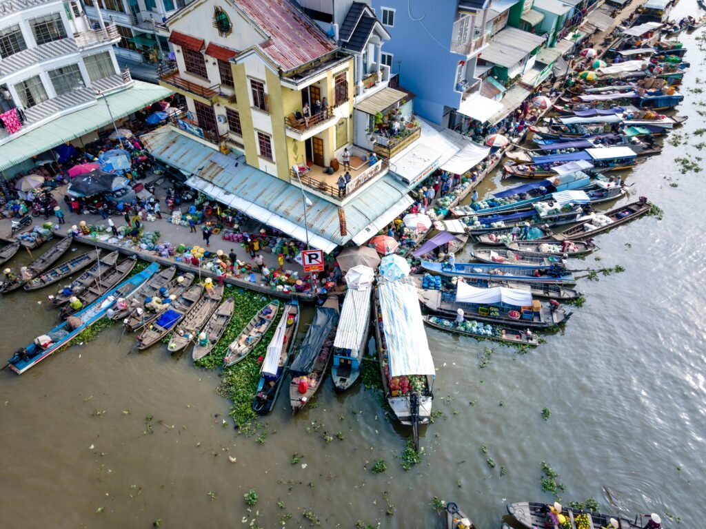 Colorful floating market scene with docked boats and bustling activity on a riverside.